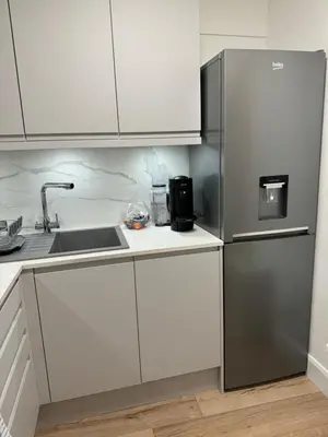 a kitchen with a stainless steel refrigerator and white cabinets at Luxury Apartment in Letchworth in Letchworth