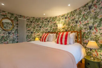 a bedroom with a white bed with floral wallpaper at A fairy-tale luxurious cottage - The Tea Caddy in Colchester