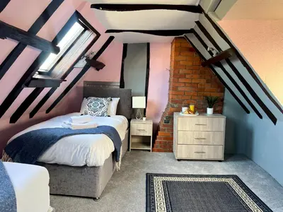 a bedroom with a bed and a chair in a attic at Duchess Apt 2 Modern 3Bedroom Apartment in Colchester Ideal for Long Stays, Relocations, Contractors, Secure Parking, WIFI in Colchester