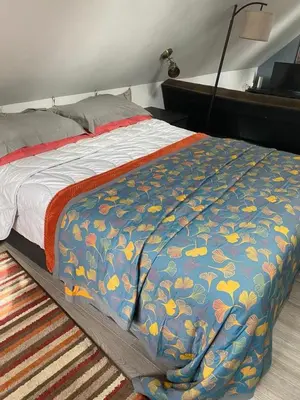 a bed with a blue and yellow blanket on it at Mulleys Cottage (Bed and Breakfast) in Westleton