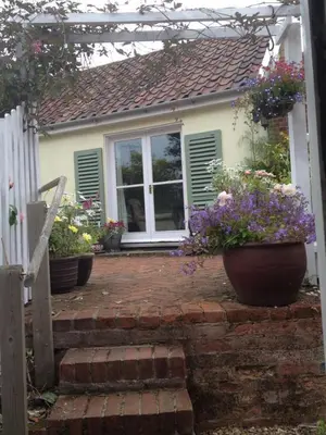 a house with three pots of flowers on the front porch at Mulleys Cottage (Bed and Breakfast) in Westleton
