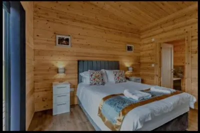 a bedroom with a bed in a log cabin at Meadow Valley Lodge 2 in Hintlesham