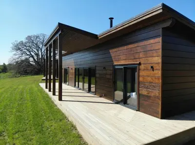 a building with a wooden deck next to a field at Meadow Valley Lodge 2 in Hintlesham