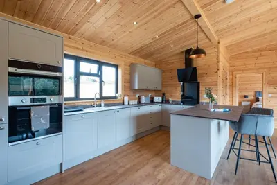 a kitchen with white cabinets and a wooden ceiling at Meadow Valley Lodge 2 in Hintlesham