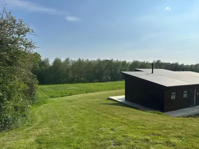 a small black building on a grassy field at Meadow Valley Lodge 2 in Hintlesham