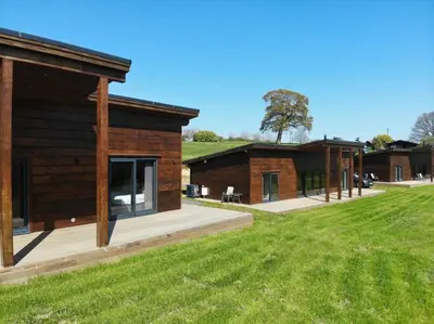 a log cabin with a grassy field in front of it at Meadow Valley Lodge 2 in Hintlesham