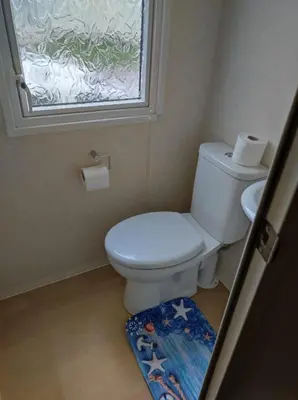 a bathroom with a toilet with a window and a rug at Dovercourt holiday park swift johnson low road harwich essex co12 3TZ in Parkeston