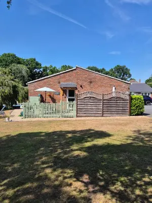 a brick building with a fence and an umbrella at The Woodpeckers - Alresford Essex in Alresford