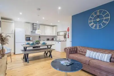 a living room with a couch and a clock on a wall at Luxe Cambridge Station Flat with Terrace in Cambridge