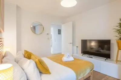 a living room with a bed and a flat screen tv at Luxe Cambridge Station Flat with Terrace in Cambridge