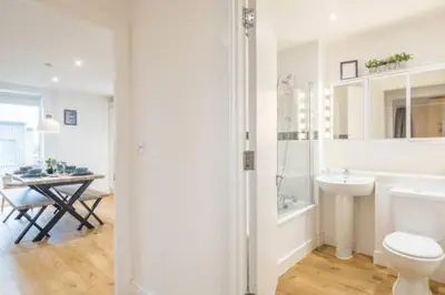 a white bathroom with a toilet and a sink at Luxe Cambridge Station Flat with Terrace in Cambridge