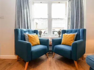 two blue chairs in a living room with a window at Fawcett Cottage in Aldeburgh