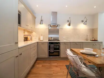 a kitchen with white cabinets and a wooden table at Fawcett Cottage in Aldeburgh