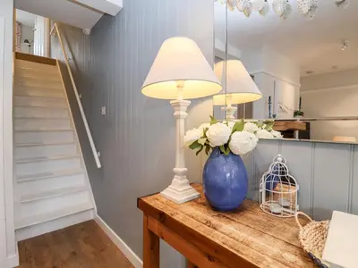 a table with two lamps and a blue vase with flowers at Fawcett Cottage in Aldeburgh