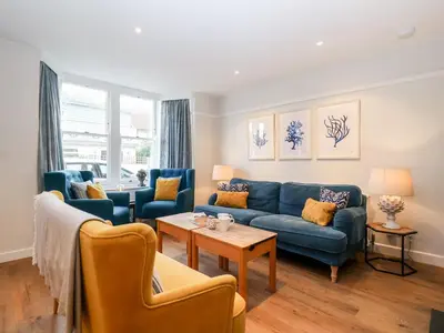 a living room with a blue couch and chairs at Fawcett Cottage in Aldeburgh