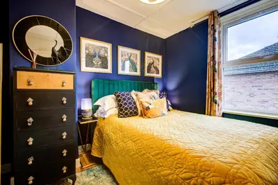 a bedroom with blue walls and a bed and a window at Chic Cottage Fireplace Patio Pet Train Stn in Wivenhoe
