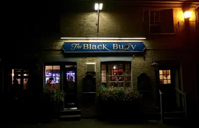 a brick building with a blue sign in the dark at Chic Cottage Fireplace Patio Pet Train Stn in Wivenhoe