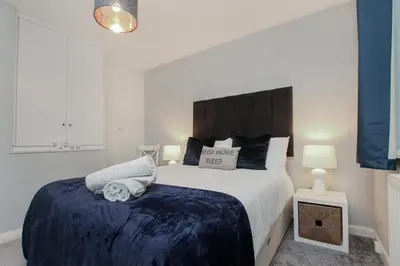 a bedroom with a large bed with a blue blanket at Hurrell House in Boreham