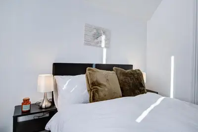 a bedroom with a white bed with two lamps at Modern 5 Bed House with Parking in Colchester