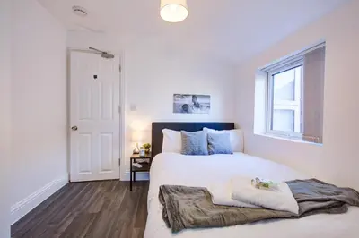 a white bedroom with a bed and a window at Modern 5 Bed House with Parking in Colchester