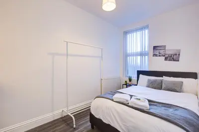a bedroom with a large bed and a window at Modern 5 Bed House with Parking in Colchester