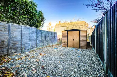a wooden shed in the side of a fence at Modern 5 Bed House with Parking in Colchester