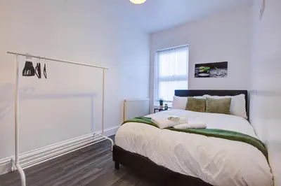 a bedroom with a large bed with white walls at Modern 5 Bed House with Parking in Colchester