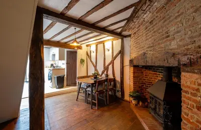 a dining room with a table and a brick wall at Charming 2 bedroom property in Bury Saint Edmunds