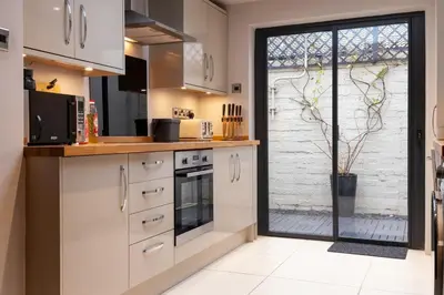 a kitchen with white cabinets and a sliding glass door at Charming 2 bedroom property in Bury Saint Edmunds