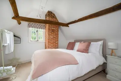 a bedroom with a white bed and a brick wall at Dragonfly Cottage, Long Melford in Long Melford