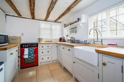 a kitchen with white cabinets and a red stove top oven at Dragonfly Cottage, Long Melford in Long Melford