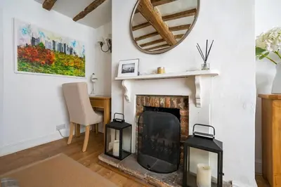 a living room with a fireplace and a mirror at Dragonfly Cottage, Long Melford in Long Melford