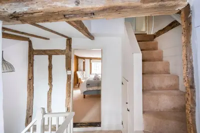 a staircase in a room with white walls and wooden beams at Dragonfly Cottage, Long Melford in Long Melford