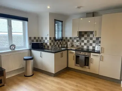 a kitchen with white cabinets and black counter tops at Modern The Mews Apartment in Bury Saint Edmunds