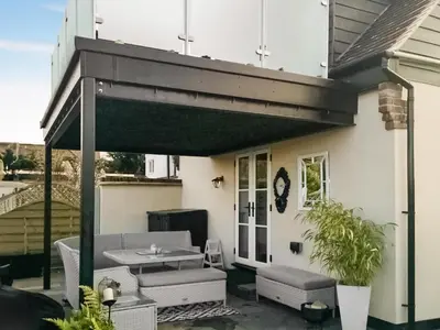 awning over a patio with a table and chairs at Rose Cottage in Peldon