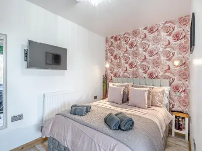a bedroom with a large bed with pink roses on the wall at Rose Cottage in Peldon