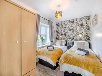 a bedroom with two beds and a window at Rose Cottage in Peldon