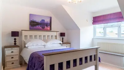 a bedroom with a bed and two windows at Superb 4BD Stay in Wyton and Houghton Village in Wyton