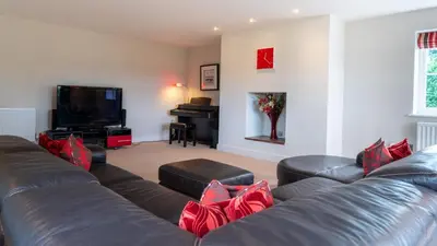 a living room with a leather couch and a television at Superb 4BD Stay in Wyton and Houghton Village in Wyton