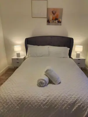 a plastic bottle laying on a bed with two lamps at 2 bedroom en-suite apartment in Basildon, Essex (Enjoy the simple things in life) in Laindon