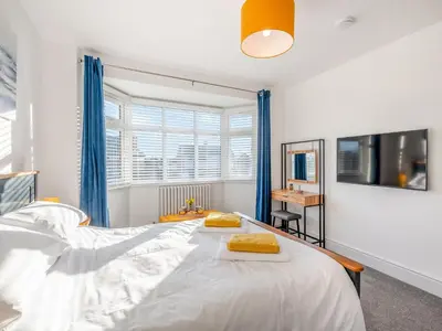 a bedroom with a large white bed with blue curtains at Coastal Gem in Clacton-on-Sea