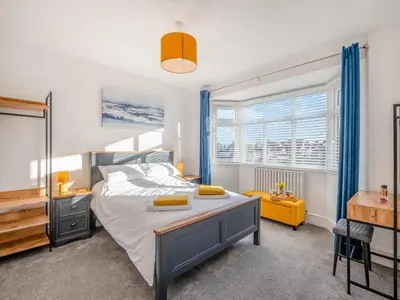 a bedroom with a bed and a desk and a window at Coastal Gem in Clacton-on-Sea