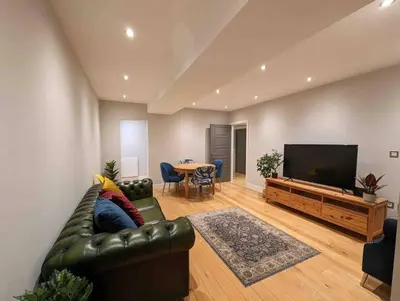 a living room with a leather couch and a television at Elegant Central Brentwood Flat in Brentwood