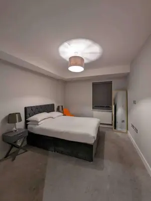 a bedroom with a large bed and a lamp at Elegant Central Brentwood Flat in Brentwood