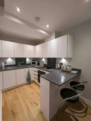 a kitchen with white cabinets and black counter tops at Elegant Central Brentwood Flat in Brentwood