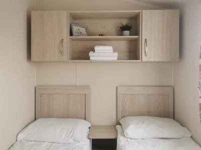 two beds in a room with cabinets and towels at Cosy 3 Bedroom Beachfront Getaway in Mersea in West Mersea