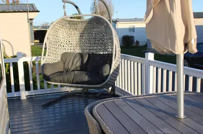 a chair sitting on a deck on a porch at Cosy 3 Bedroom Beachfront Getaway in Mersea in West Mersea