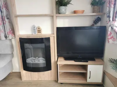 a television on a wooden stand in a living room at Cosy 3 Bedroom Beachfront Getaway in Mersea in West Mersea