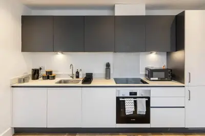 a kitchen with white cabinets and black appliances at Chelmsford Centre View Sleep 4 Next Chelmer canal in Chelmsford