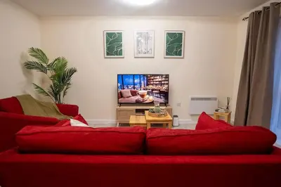 a living room with a red couch and a tv at Cosy 2 Bedroom flat in Stevenage in Stevenage